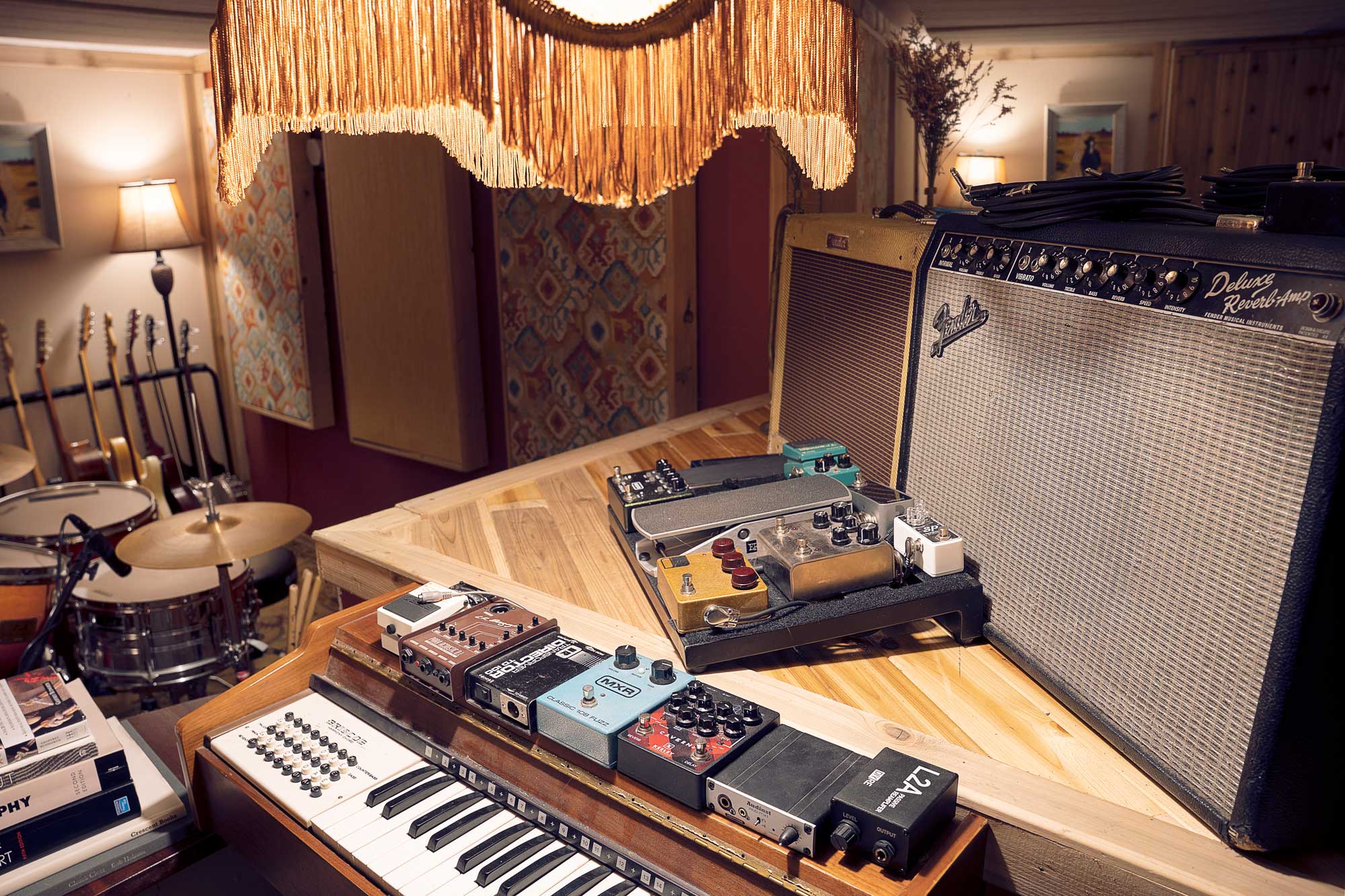 guitar pedals sitting on top of an organ in front of two guitar amps