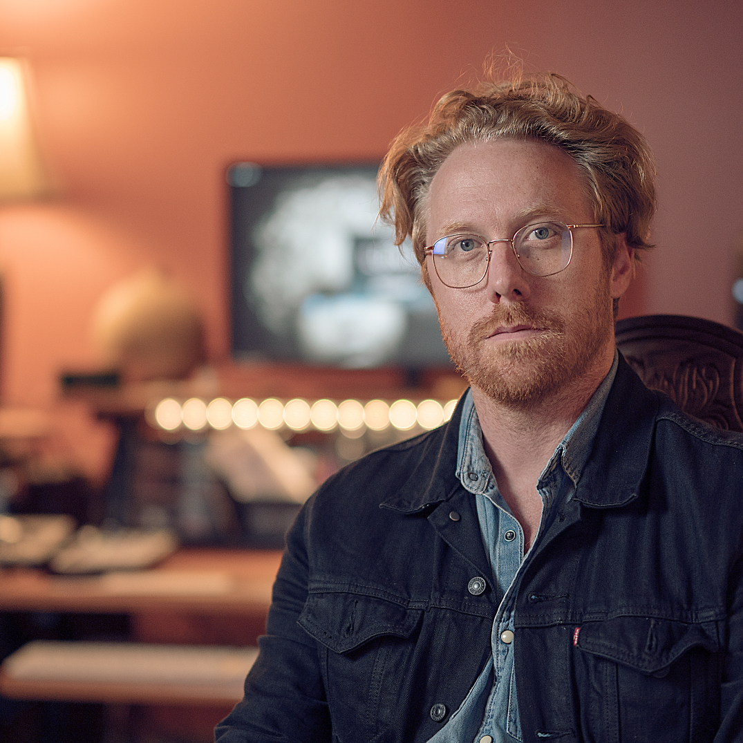 portrait chad gilmore sitting in front of sound engineer desk recording studio